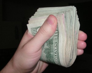 hand holding hundreds of dollars in cash