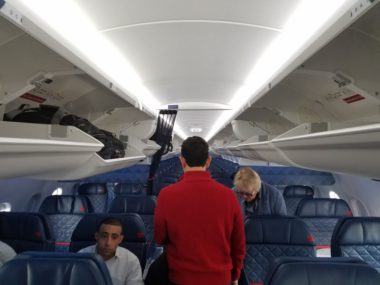 people walking through airplane cabin