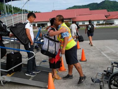 man passing bag to passenger