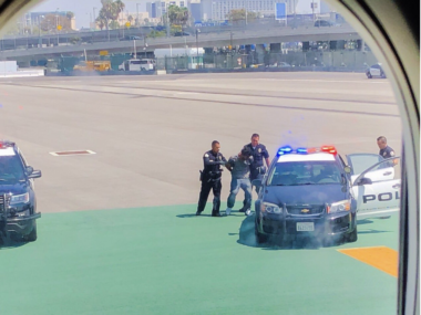man being apprehended by police on runway