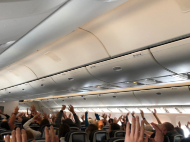 people with hands up in air on plane