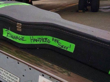 guitar with green tape that say baggage handlers are sexy